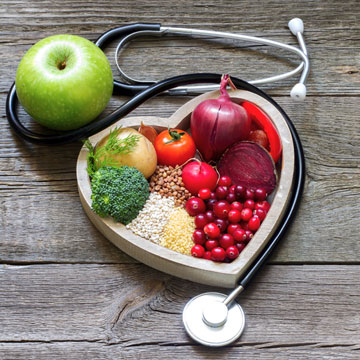 Apple, stethoscope, fruits and grains in heart-shaped bowl